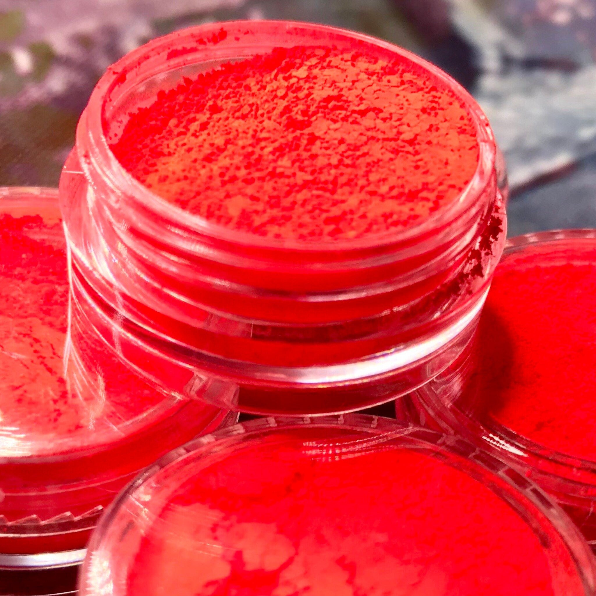 Close-up of vibrant red eyeshadow pigment with ultra-fine shimmer particles in compact pan.