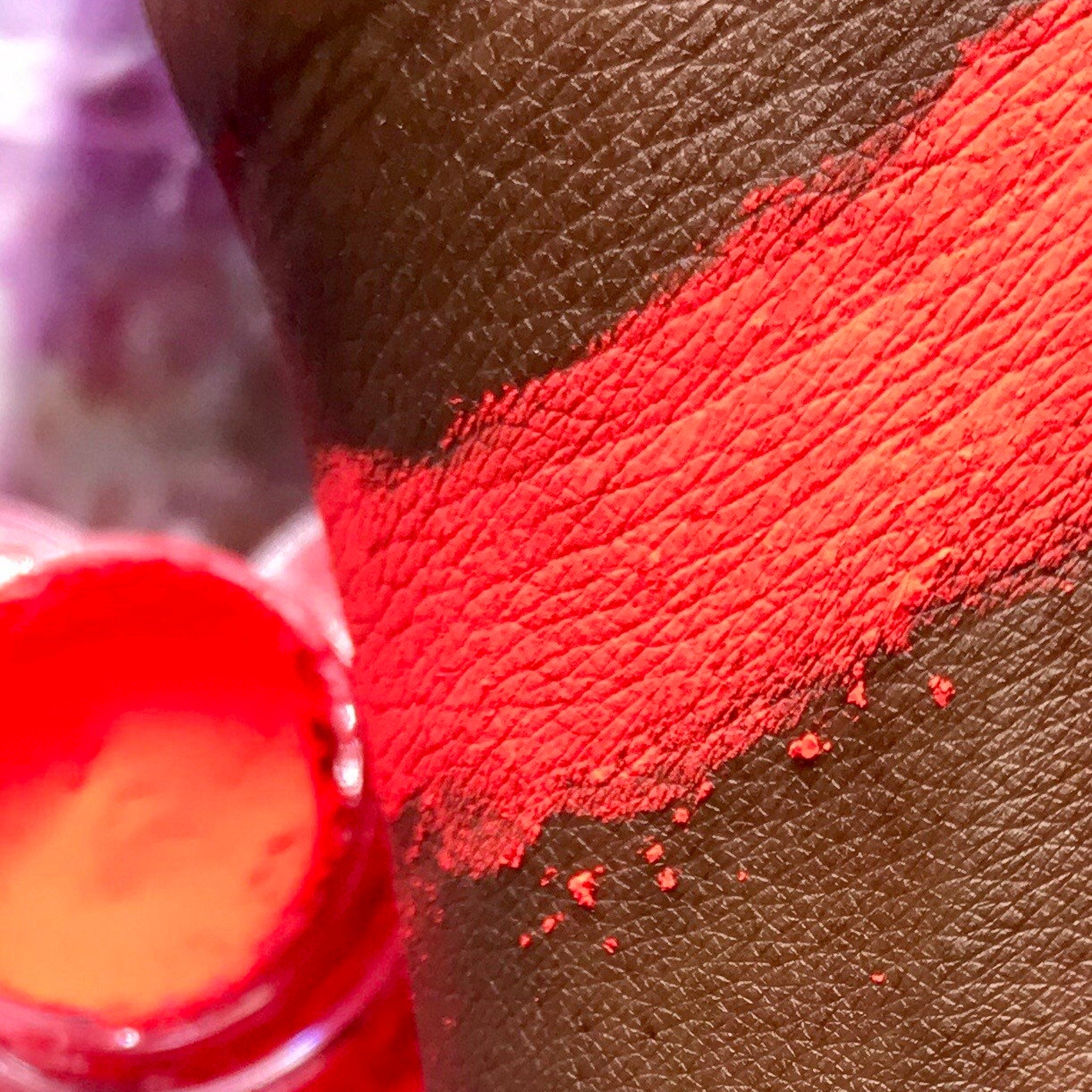 Side view of vibrant red ultra premium eyeshadow pigment pot showing rich powder texture
