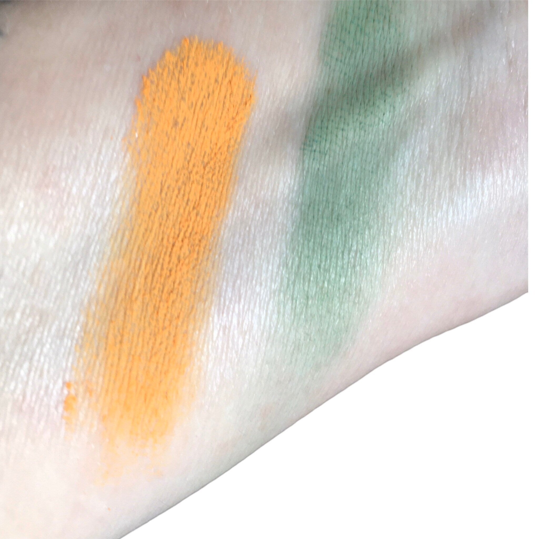 Eyeshadow swatches, orange and green powder, applied on skin for color test
