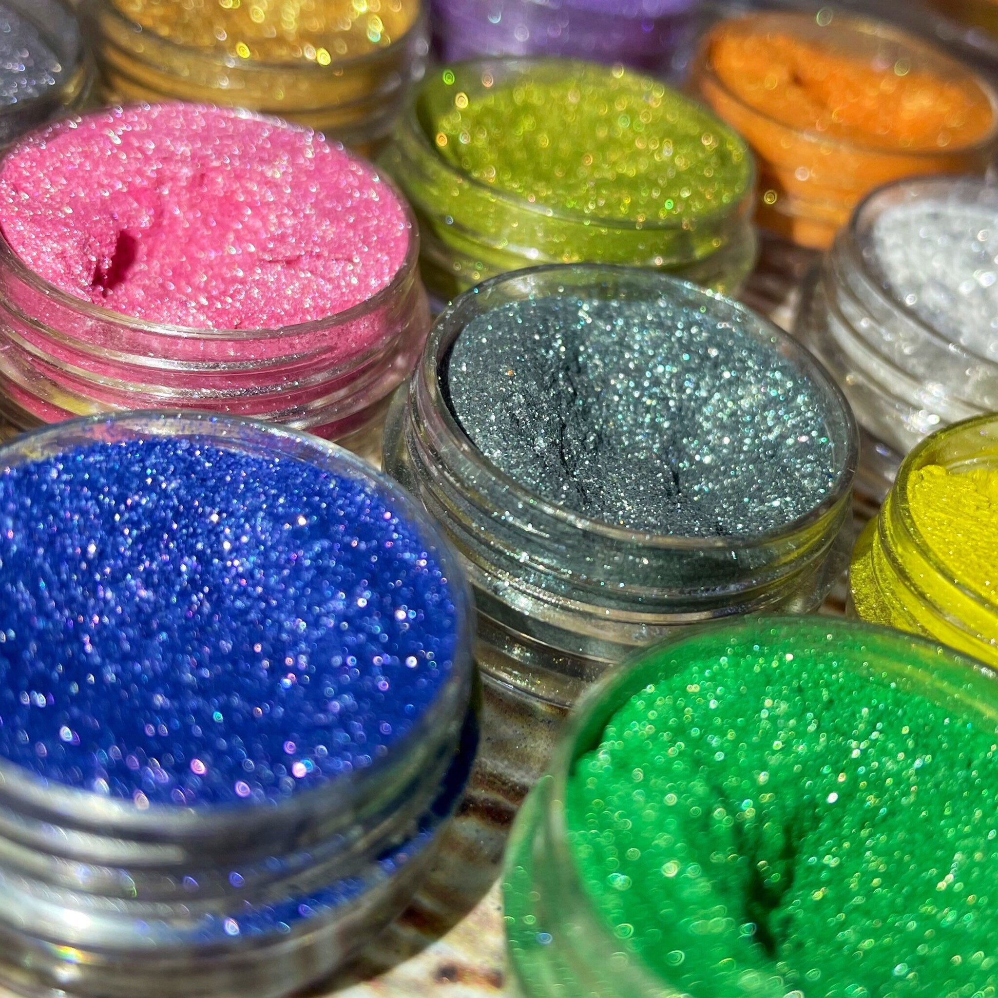 Twelve vibrant shimmery vegan eyeshadows in a sleek palette with mirrored lid and gradient hues.