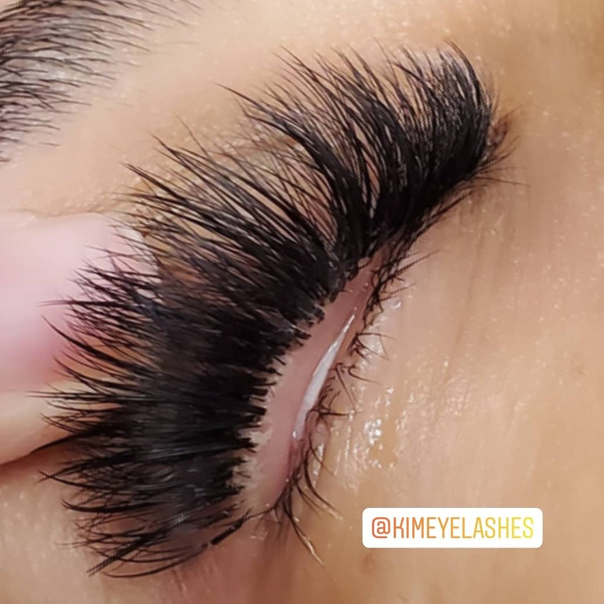 Eyelashes with black, long, layered lashes and @KIMEYELASHES text on skin