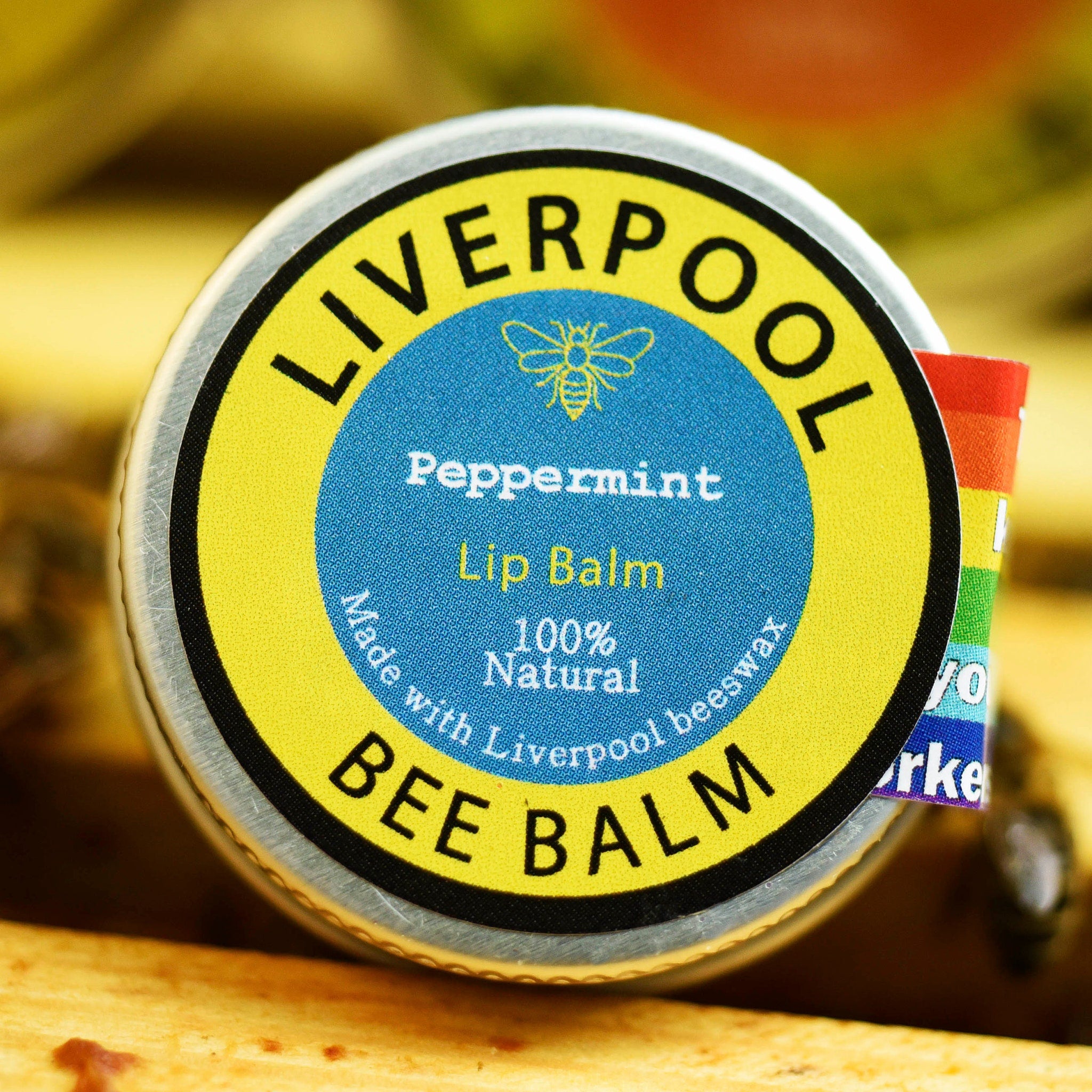 Lip balm tin with yellow and blue label, silver rim, and Liverpool Bee Balm text