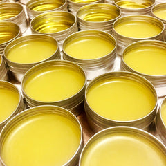Yellow balm in silver metal tins, multiple containers, close-up view