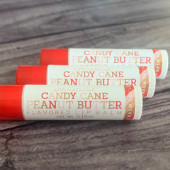 Lip balm tubes with red, white, and tan labels, text reads Candy Cane Peanut Butter, all natural flavor