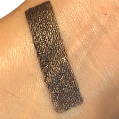 Eyeshadow swatch, dark brown metallic color, applied on skin, close-up view