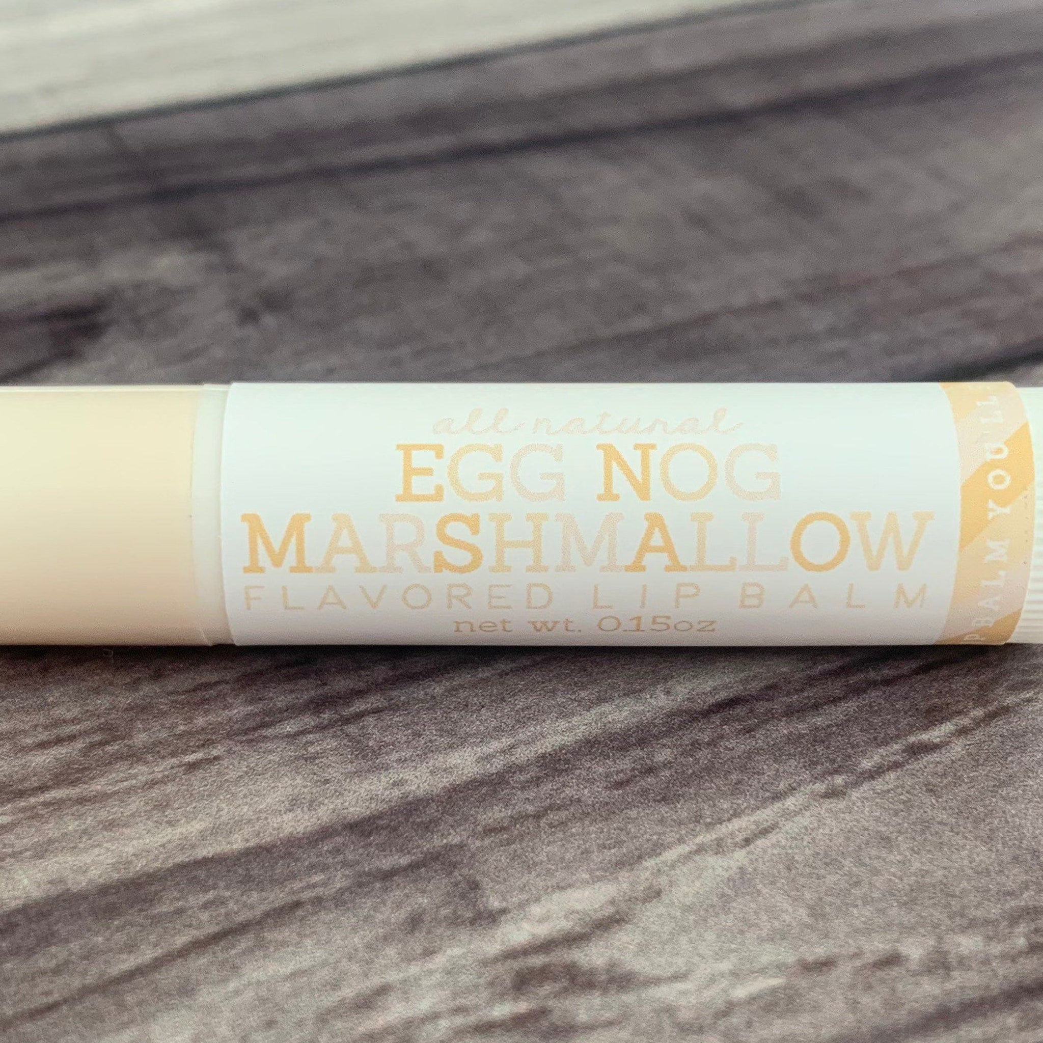 Lip balm tube with light beige color, white label, and Egg Nog Marshmallow text visible