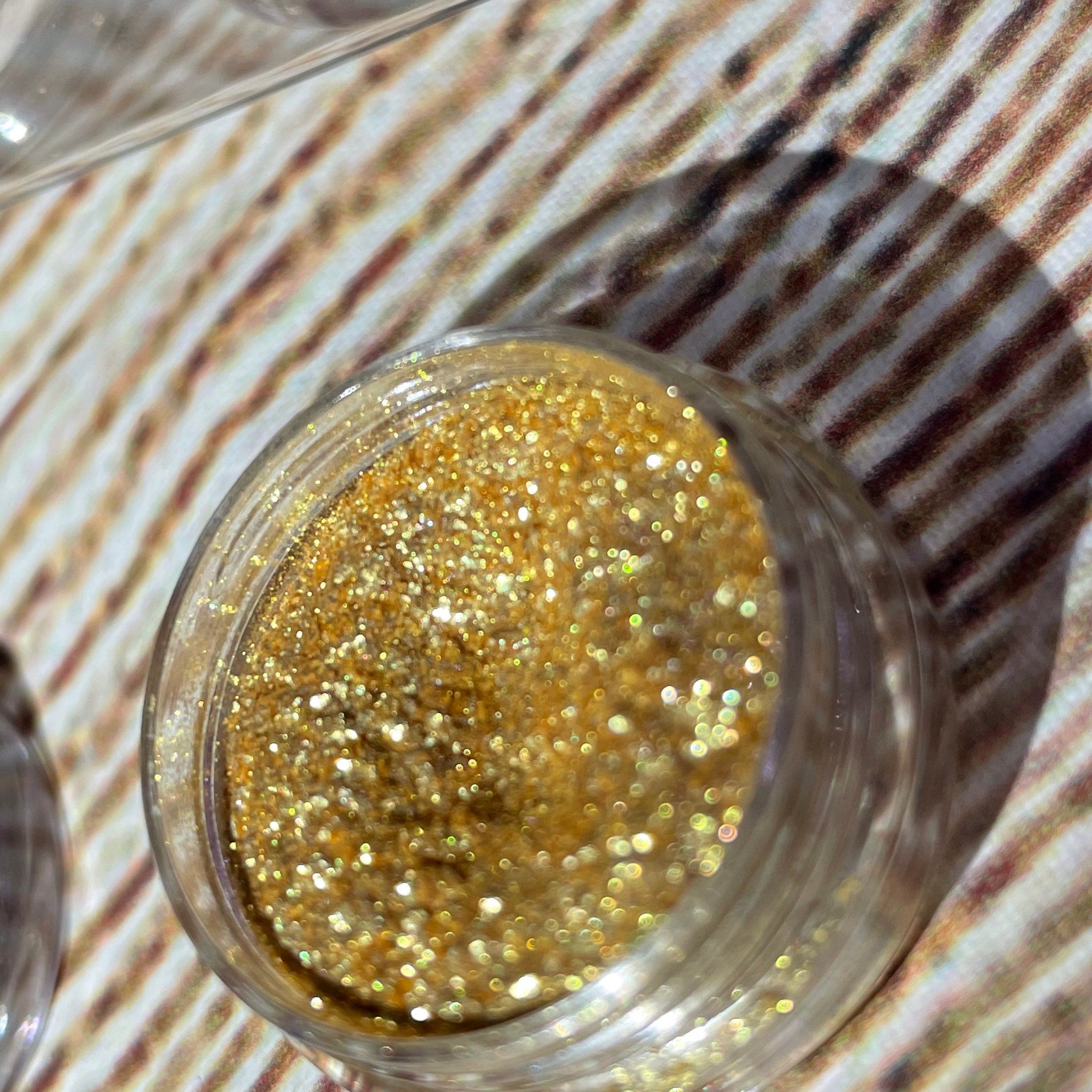 Close-up of fingertips applying shimmery bronze eyeshadow with a soft brush for a smoky eye effect