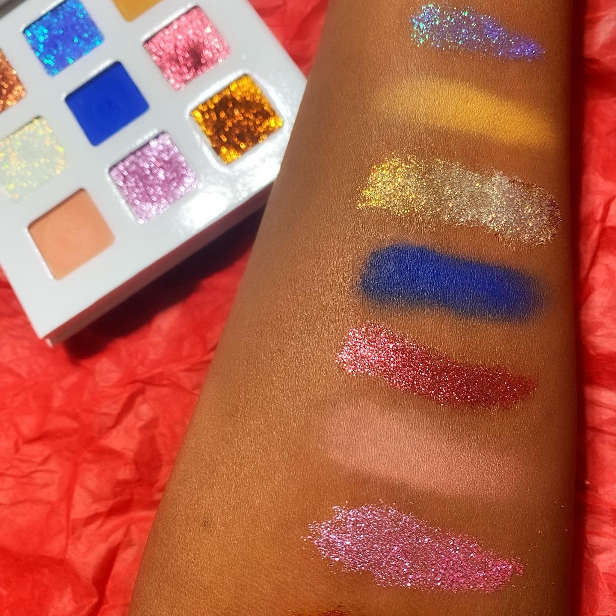 Close-up of holiday eyeshadow palette showing glitter gold and matte burgundy shades with smooth textures