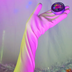 Round metal container with floral design, held by pink and yellow hand, on a purple background