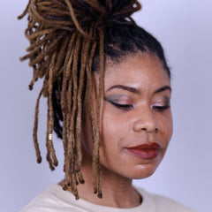 Woman applying shimmering quartz eyeshadow with fingertip to eyelid, showcasing smooth blendability