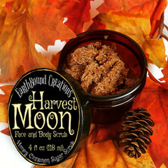 Face and body scrub in open black jar with brown granules, Harvest Moon label, and fall leaves background