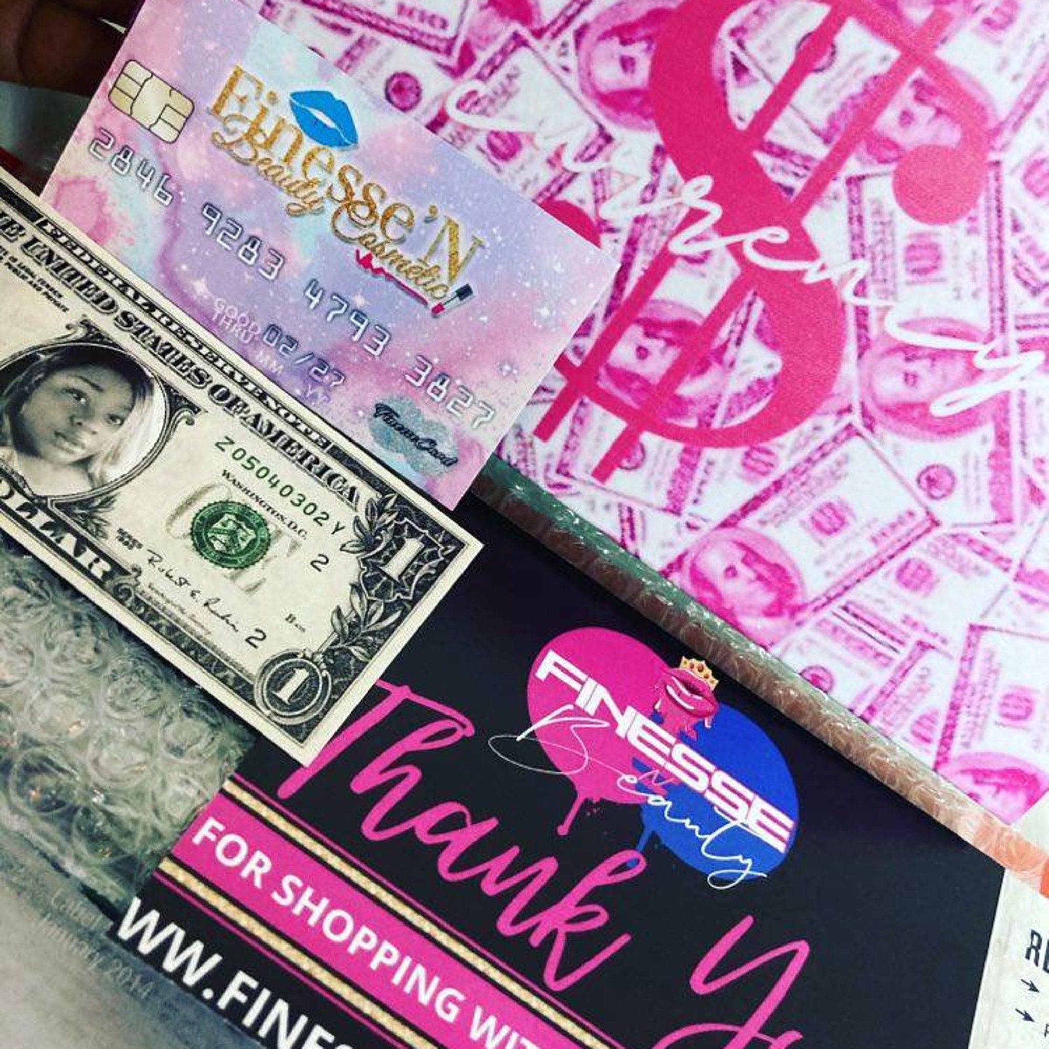 Credit card and dollar bill with pink and black branding, "Finesse N Beauty" text visible