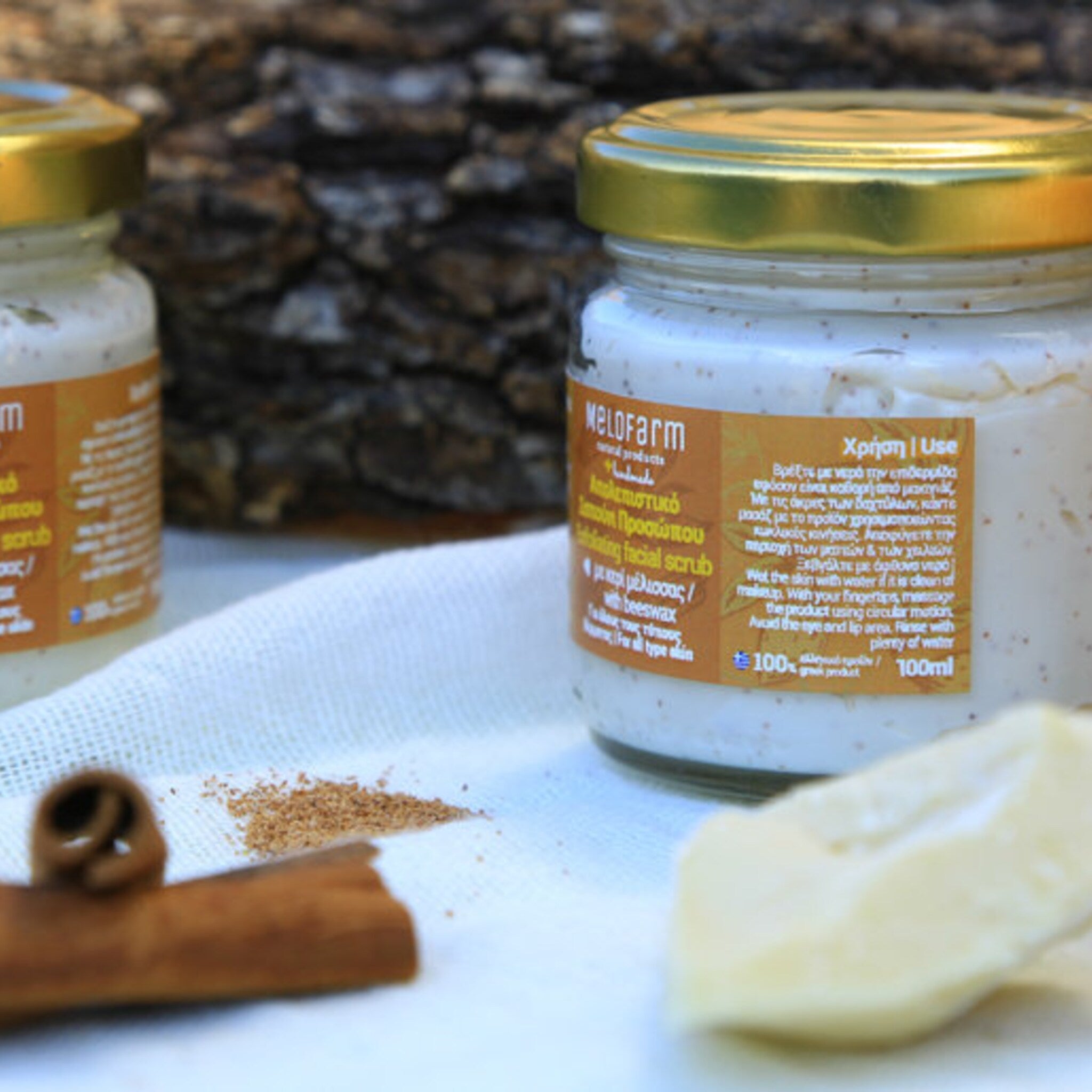 Facial scrub in glass jar with gold lid, white cream, and Melofarm label