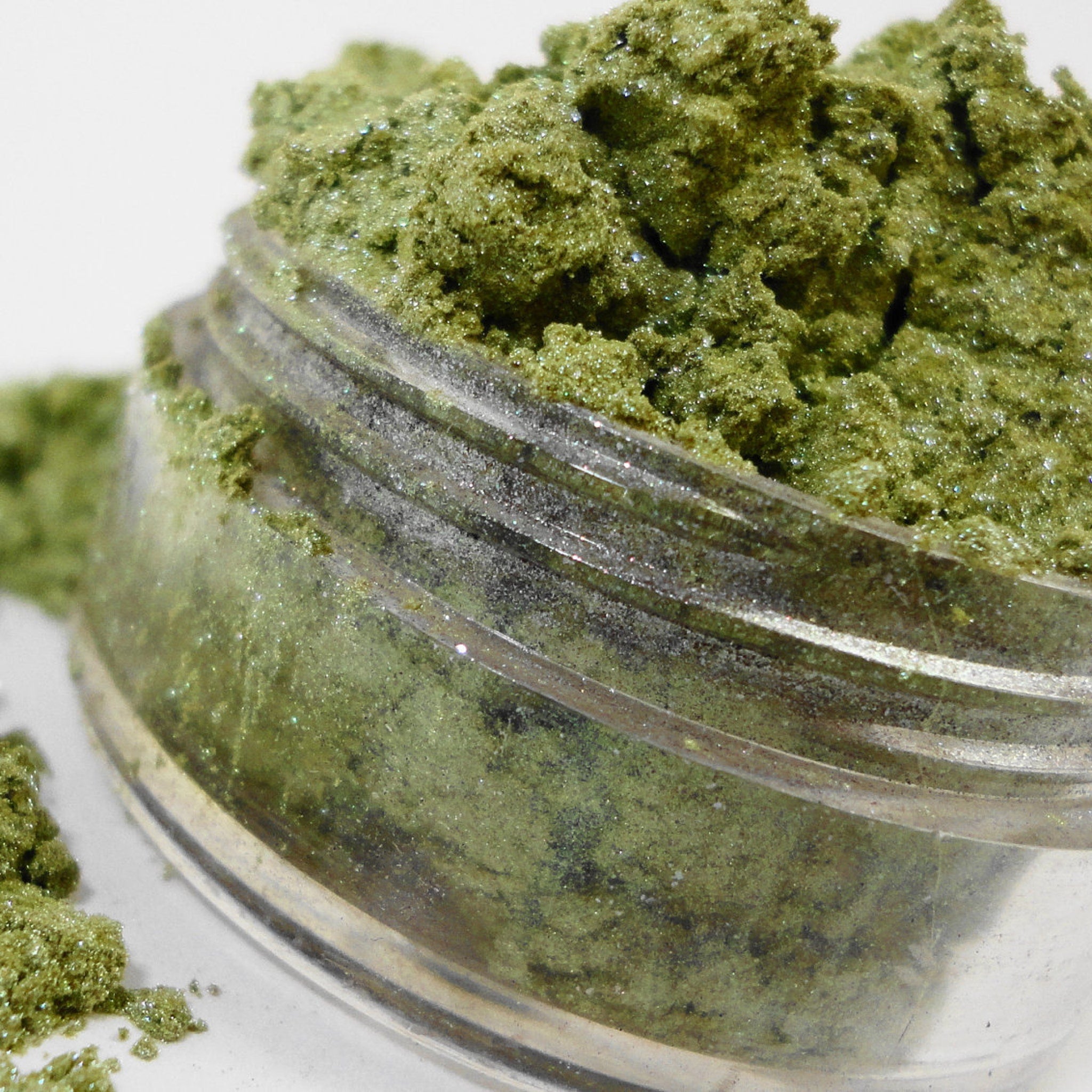 Close-up of peachy pink mineral eyeshadow powder in sifter jar showing fine shimmer texture