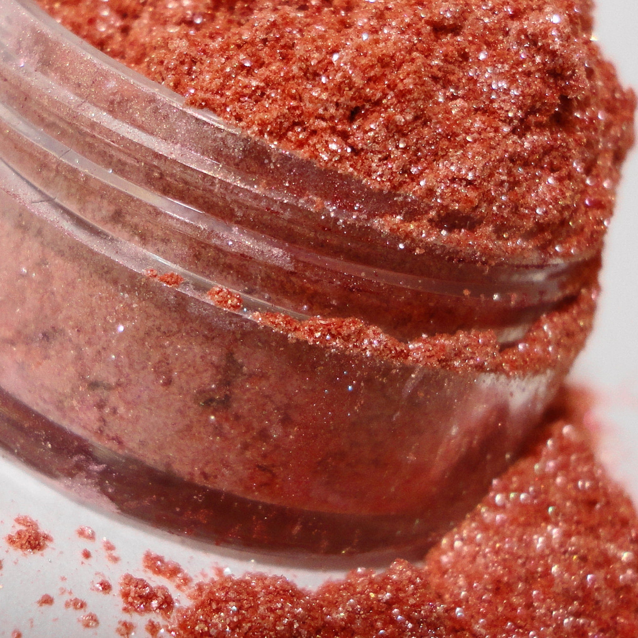Glitter eyeshadow, red-orange with sparkling particles, in clear plastic container