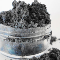 Side view of dark navy blue goth shimmer eyeshadow pan showcasing metallic luster and smooth mineral texture