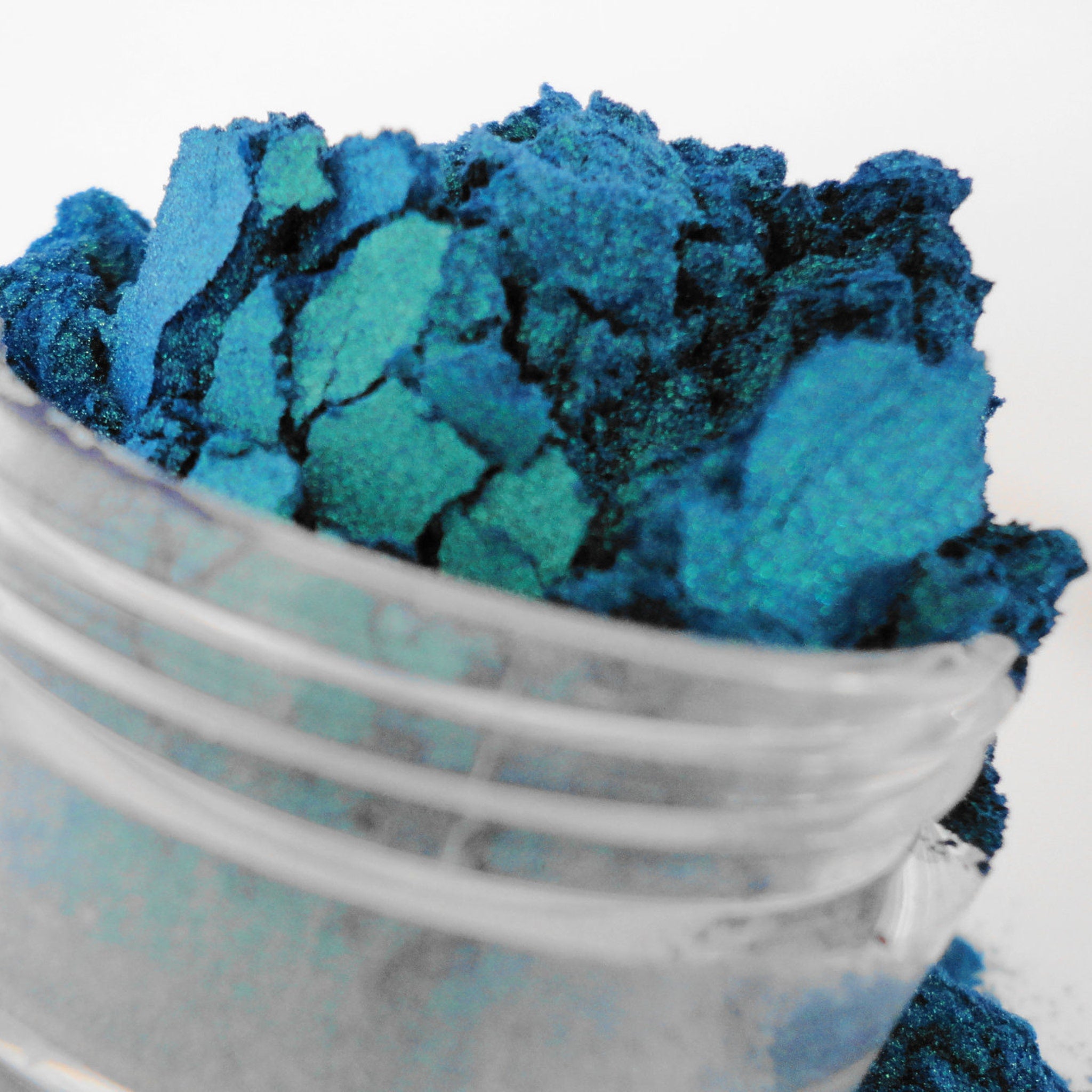 Blue powder pigment with teal highlights in a clear glass container