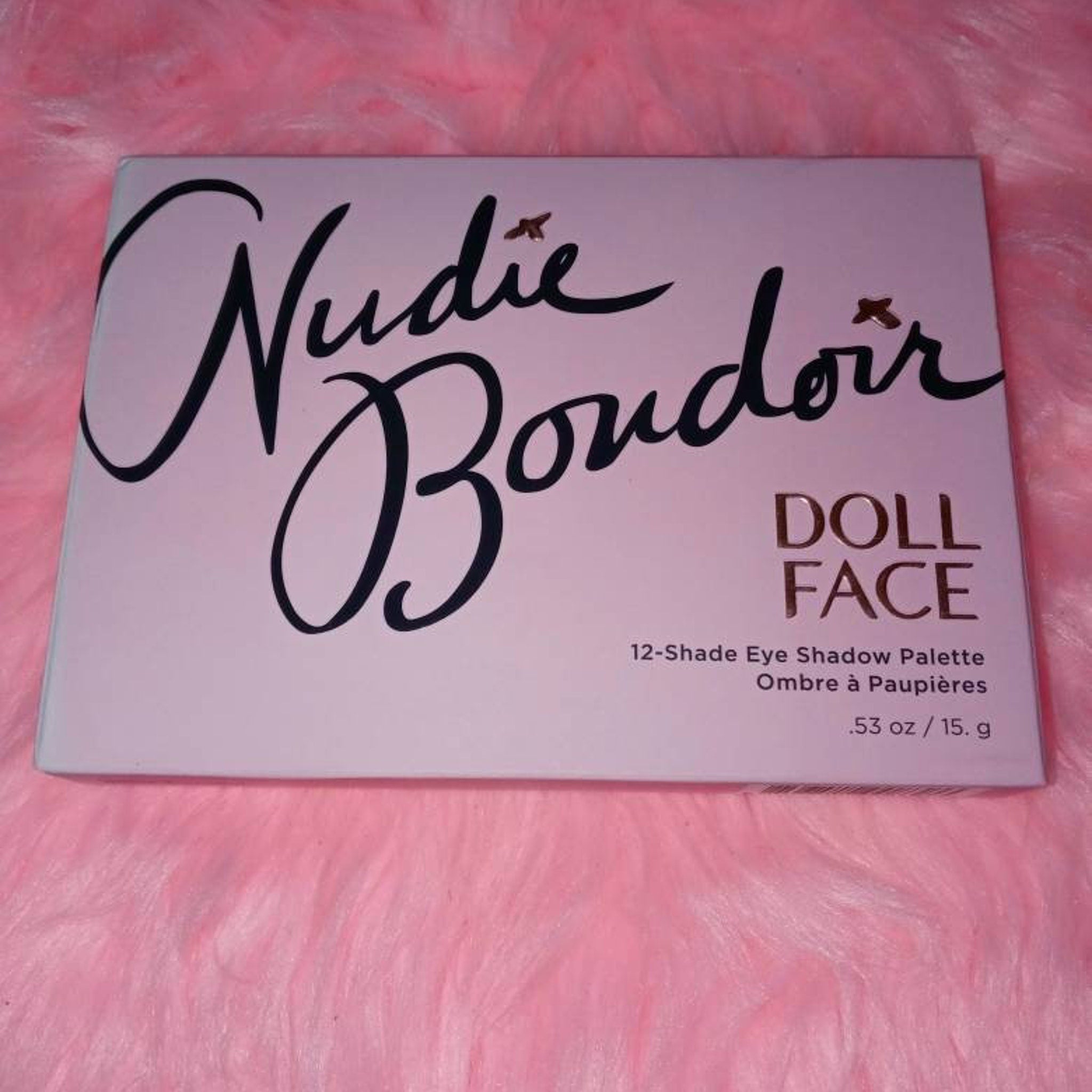 Side view of Dollface Nudie Boudoir palette showing 12 matte and shimmer nude eye shadows in rectangular pans with gold trim