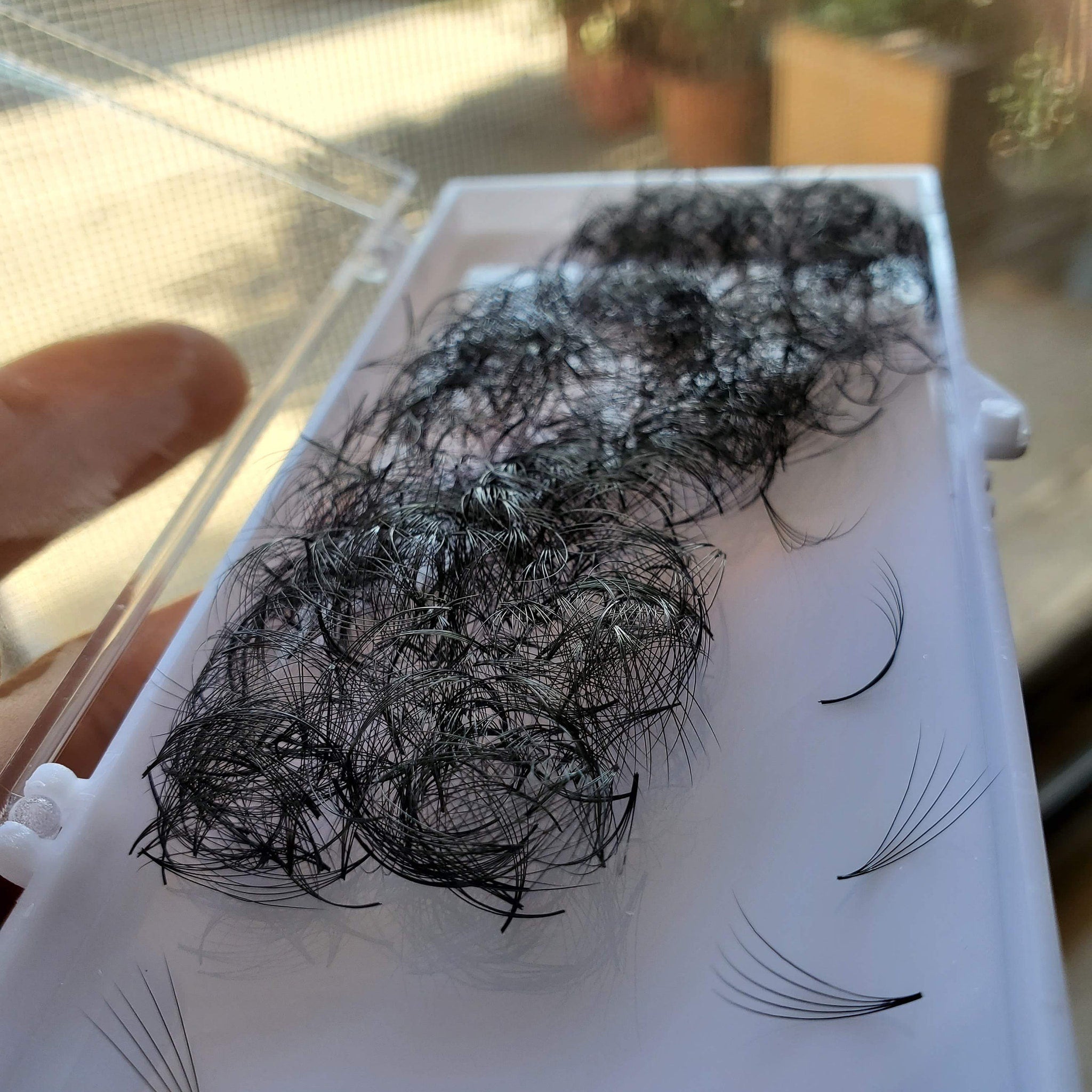 Eyelash extensions in white plastic container, black synthetic fiber, curved style