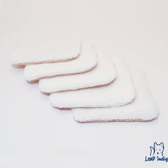 Reusable white fabric pads with pink and yellow trim, stacked on white surface