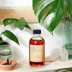 Witch Hazel bottle with brown liquid, black cap, and brand label, displayed with plants and crystals