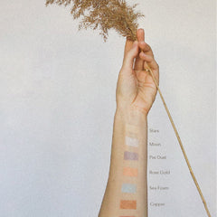 Hand applying champagne shimmer eyeshadow to eyelid with fingertip for glowing festival makeup look