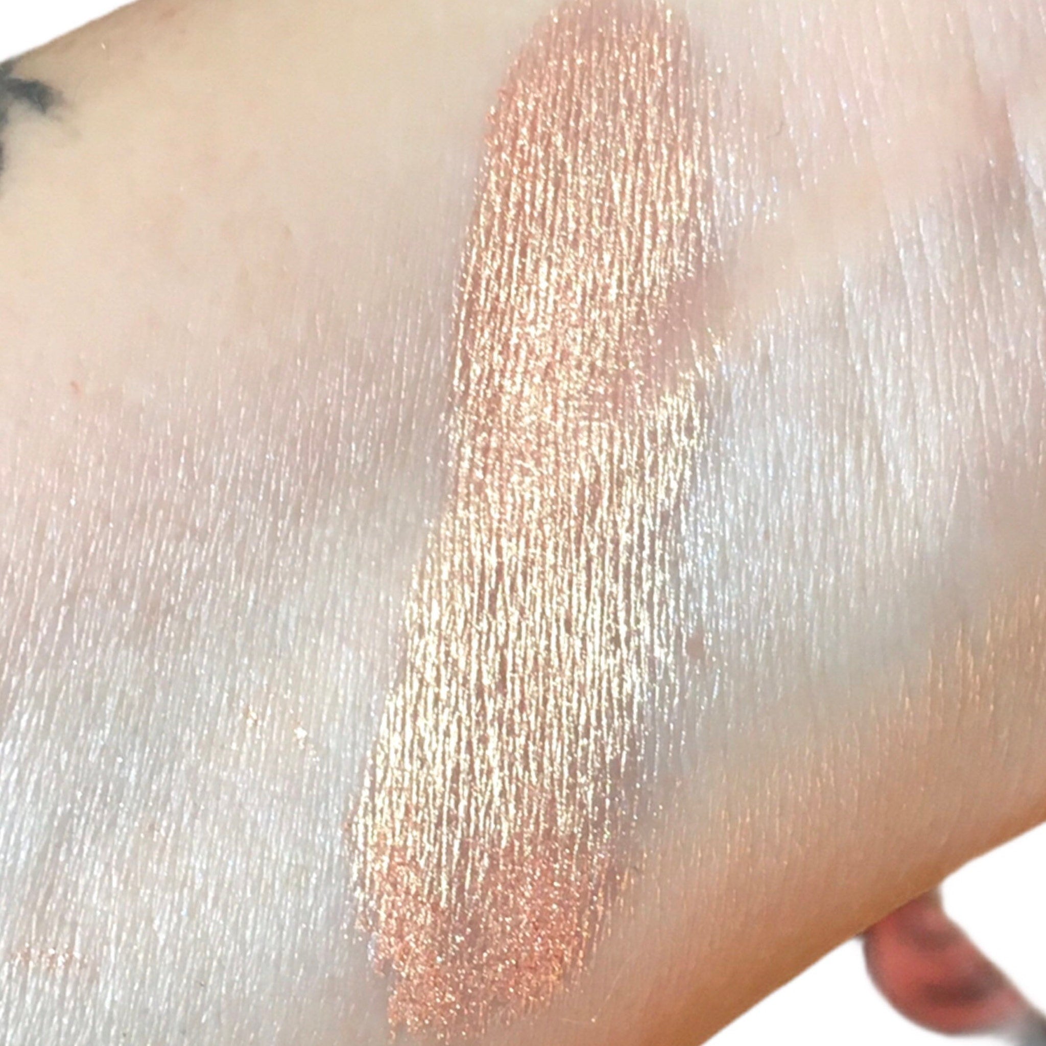 Close-up of shimmering peach eyeshadow with glitter flecks in a round 10g jar