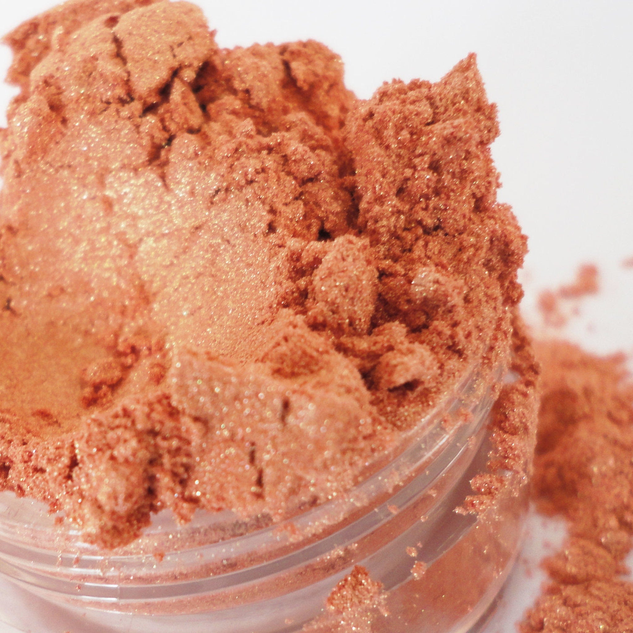 Eyeshadow shimmer peach powder in clear jar, glittery texture, for eye makeup application