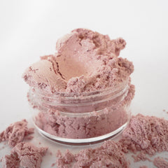 Woman applying pink coral shimmer eye shadow with fingertip, showcasing natural glitter finish from sifter jar