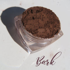 Matte brown mineral eye shadow in loose powder form with vegan label, displayed in open jar