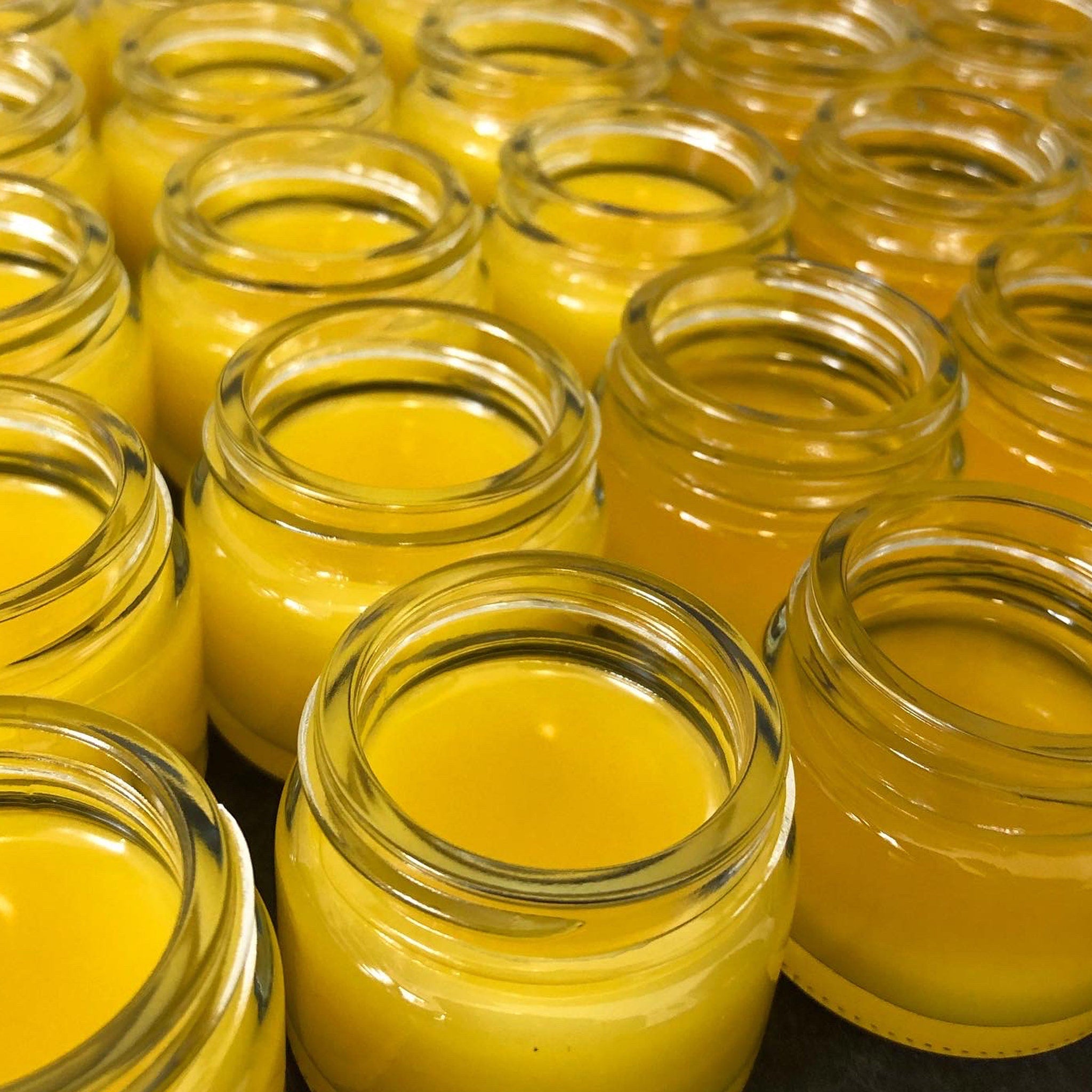 Yellow liquid in clear glass jars, close-up view of multiple containers