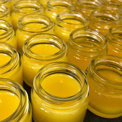 Yellow liquid in clear glass jars, close-up view of multiple containers