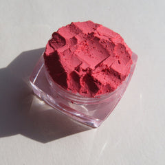Close-up of matte coral pink loose mineral eyeshadow with soft powdery texture in a vegan, talc-free formula.