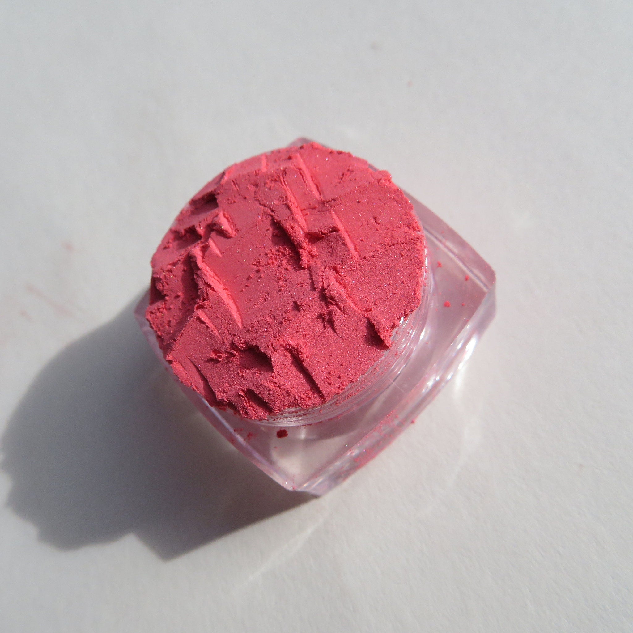 Open compact showing matte coral pink mineral eyeshadow with vegan loose pigment and mirrored interior