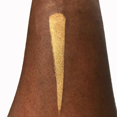 Close-up of fingertips applying shimmery bronze halo eyeshadow to eyelid with smooth metallic finish