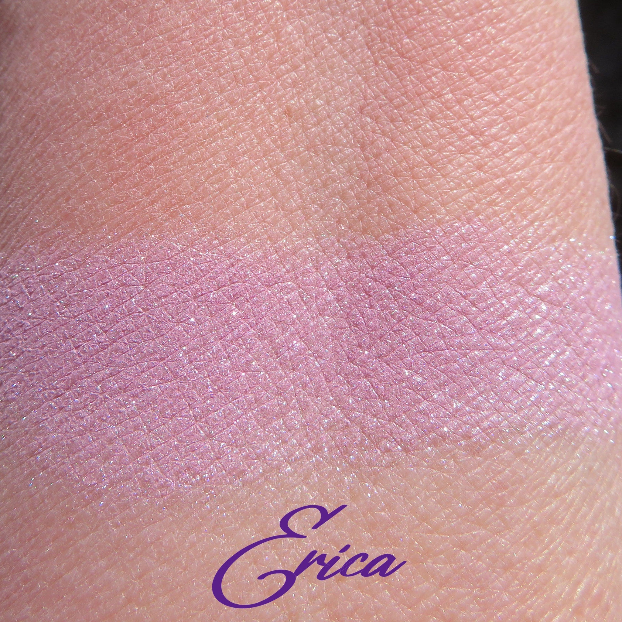 Pink eyeshadow swatch on skin with shimmer and Erica signature in purple