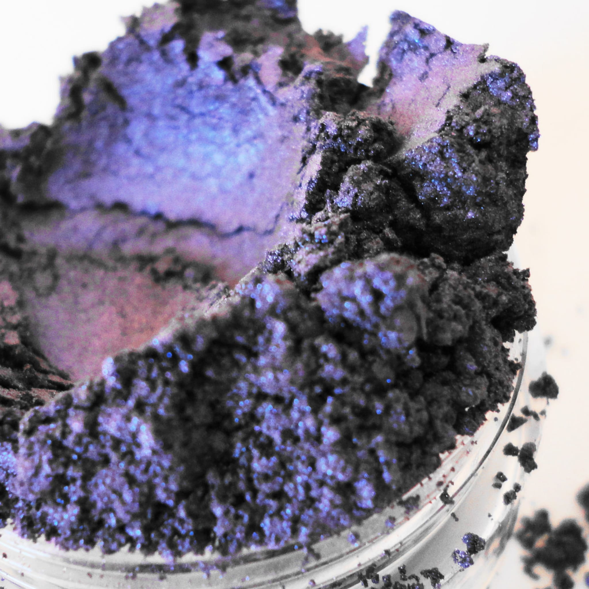 Purple eyeshadow powder with dark blue shimmer and glass container