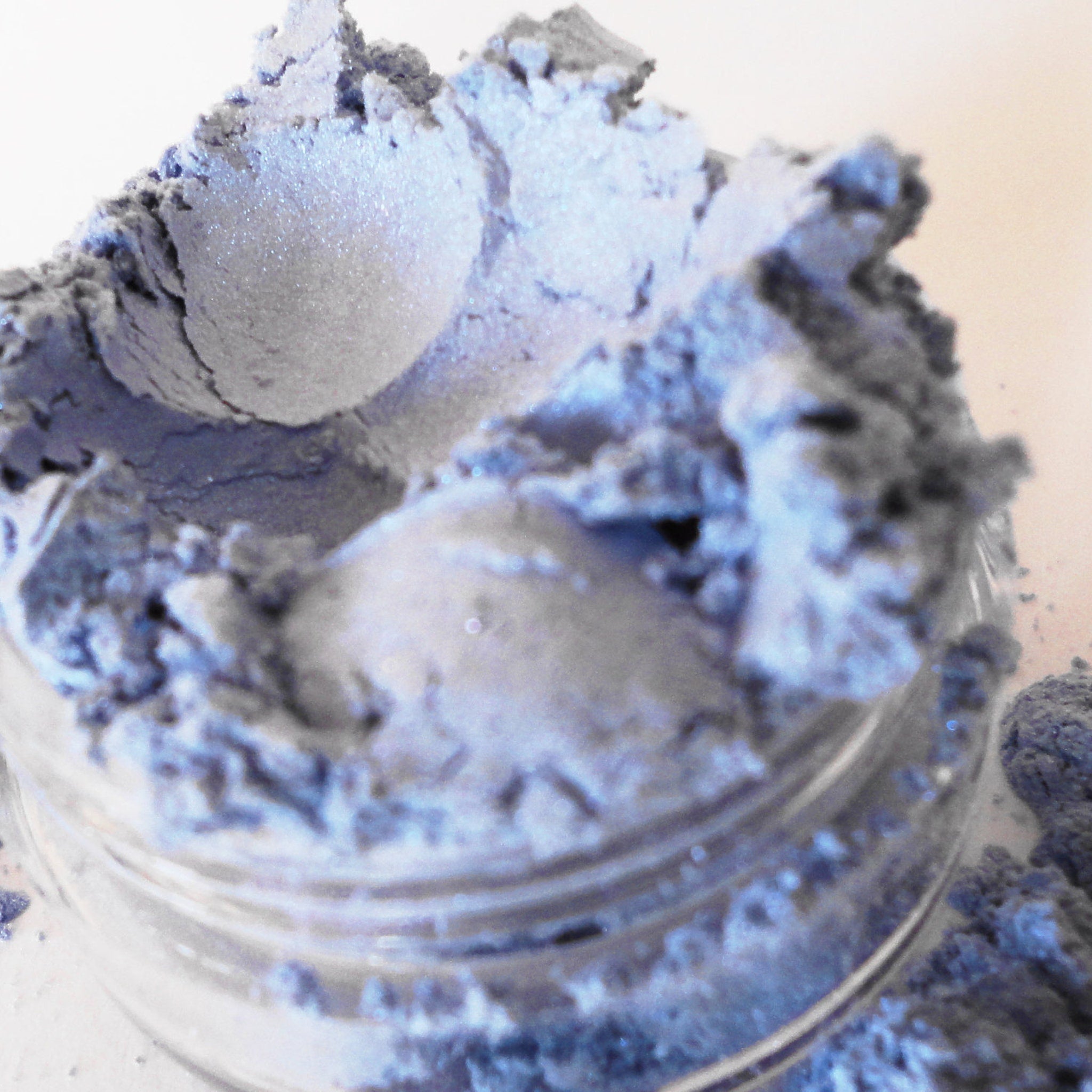 Powdered pigment in blue-gray color with iridescent shimmer, in a clear glass jar