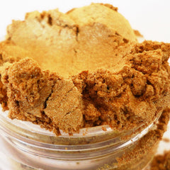 Gold eyeshadow, sparkling bronze powder, in clear jar, close-up view