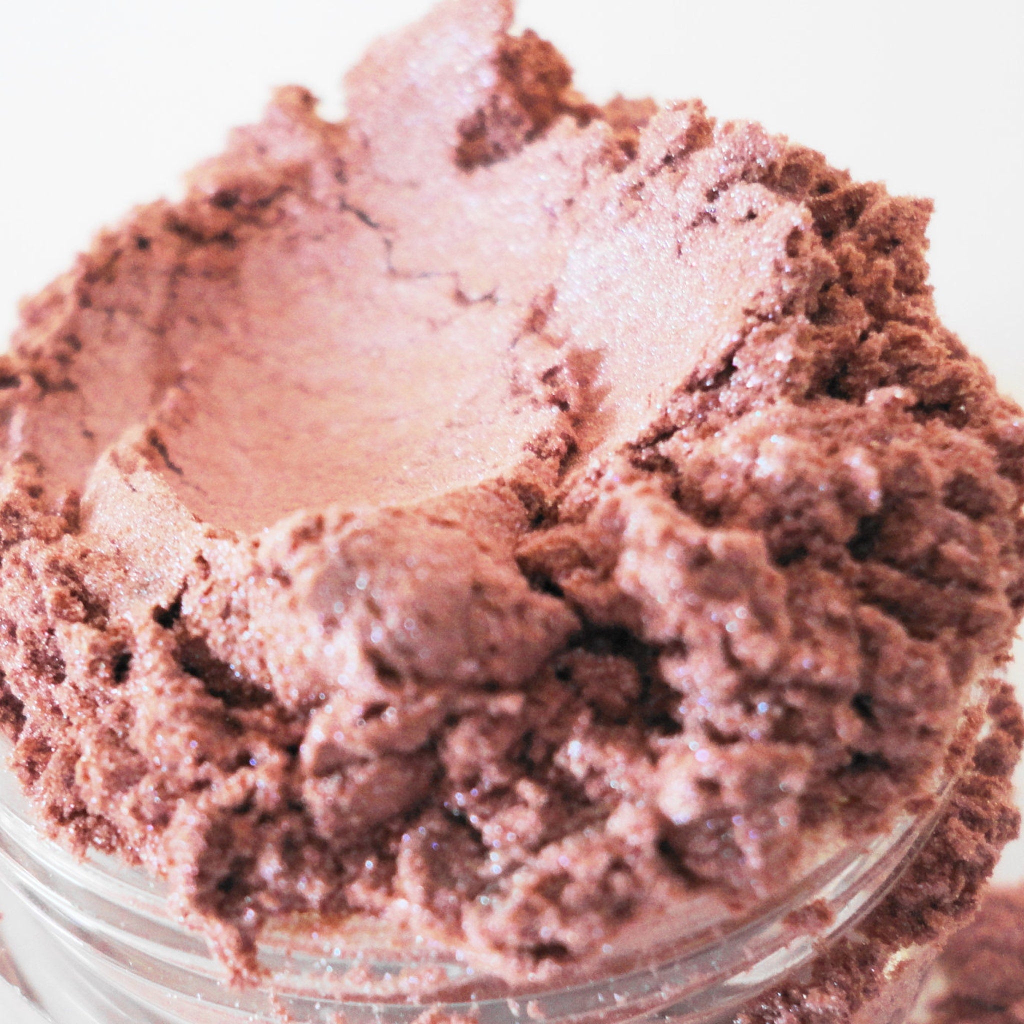 Eyeshadow dusty rose pink powder with shimmer texture in a jar