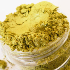 Powdered pigment in a clear plastic container, yellow-green color, granular texture, close-up view
