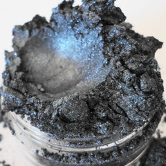 Loose eyeshadow powder in dark gray with blue shimmer, in a clear jar