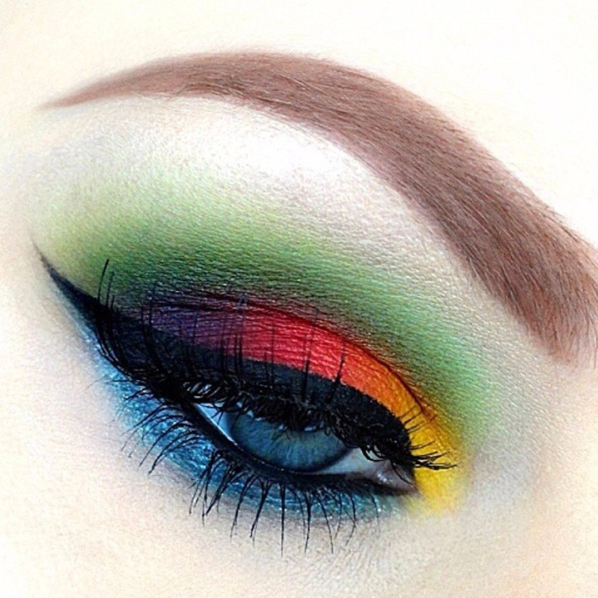 Eye makeup with rainbow eyeshadow, black eyeliner, and blue eye color for a colorful look