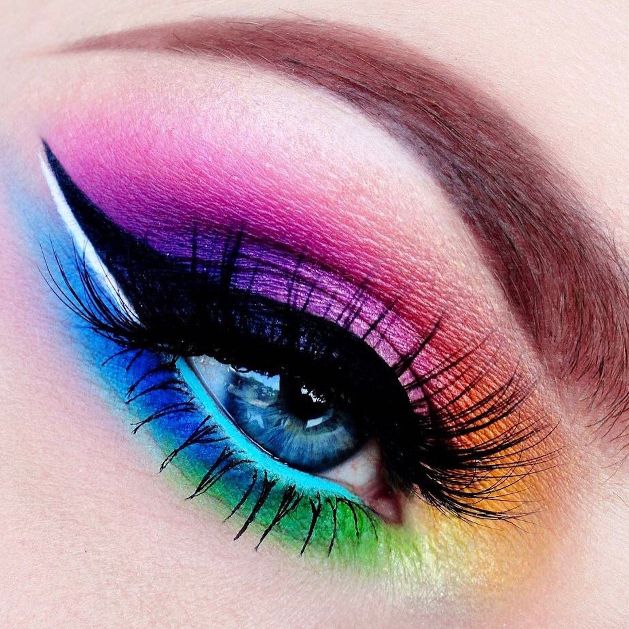 Eye makeup with rainbow eyeshadow, black eyeliner, and long black eyelashes on an eye