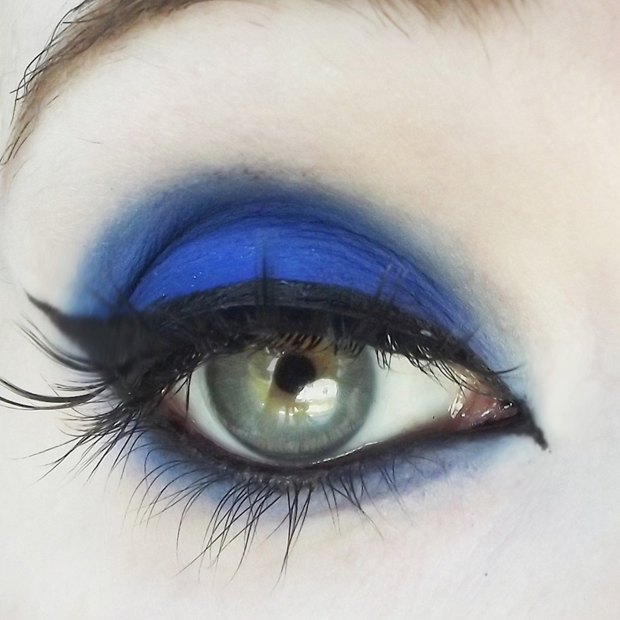 Eye makeup with blue eyeshadow and black eyeliner, visible eyelashes and green eye color