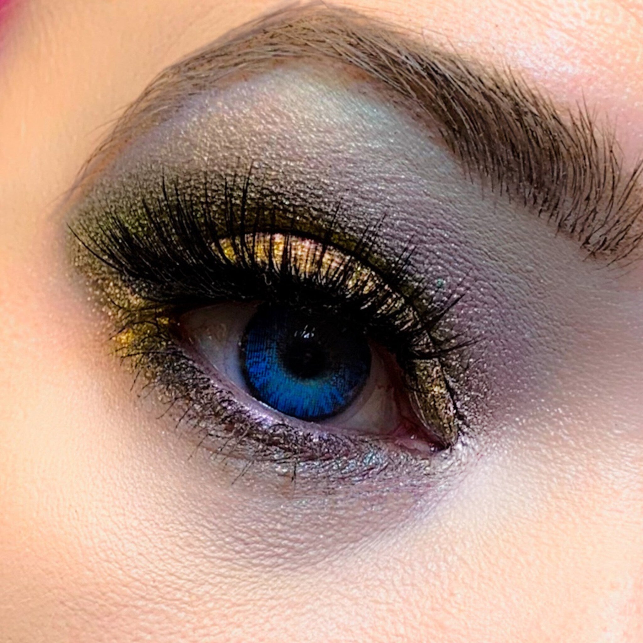 Eye makeup with blue eye, gold and purple eyeshadow, and black eyelashes