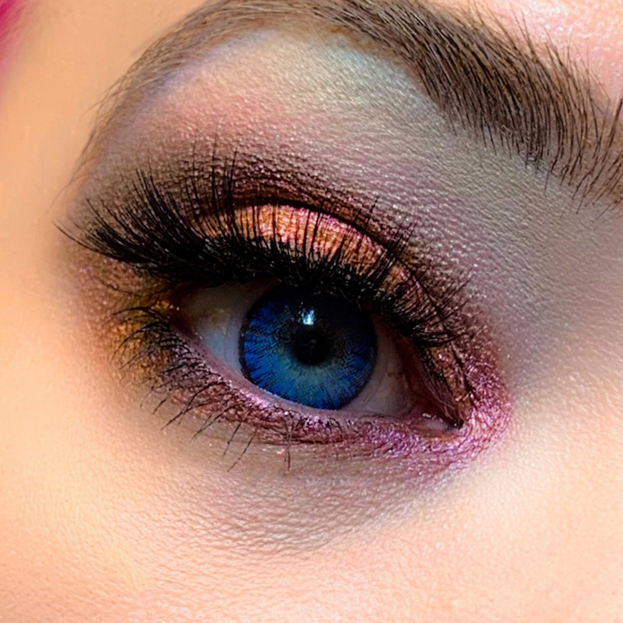 Eye makeup with blue eye, pink and brown eyeshadow, and black eyelashes