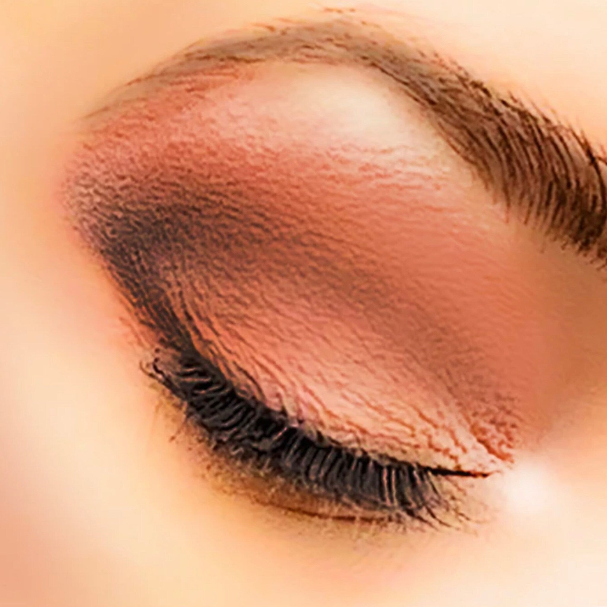 Eye makeup with brown eyeshadow, black eyelashes, and a peach skin tone