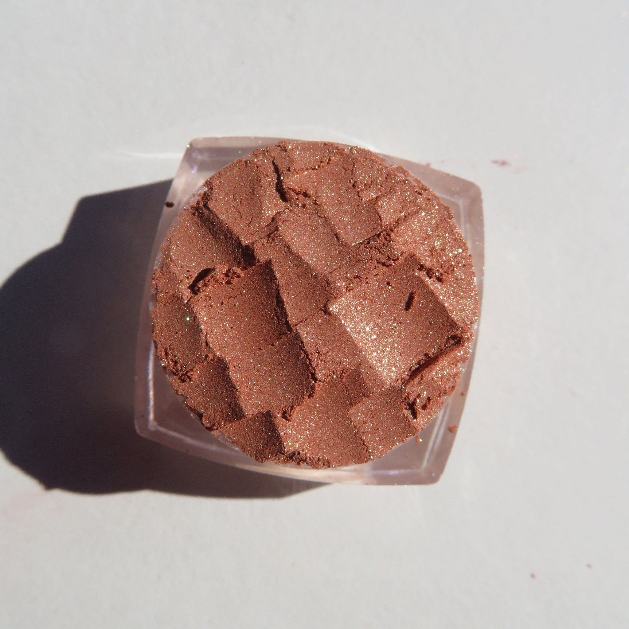 Close-up of loose brown gold mineral eyeshadow with intense golden shimmer particles, vegan and cruelty-free