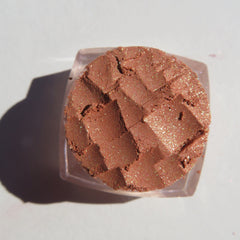 Hand applying brown gold loose mineral eyeshadow with shimmer using a makeup brush